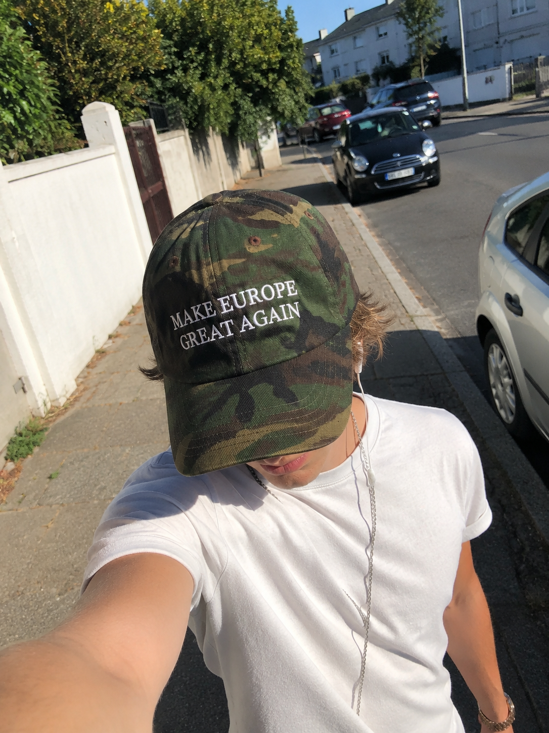 Customer wearing the camo Make Europe Great Again cap on a sunny street in France
